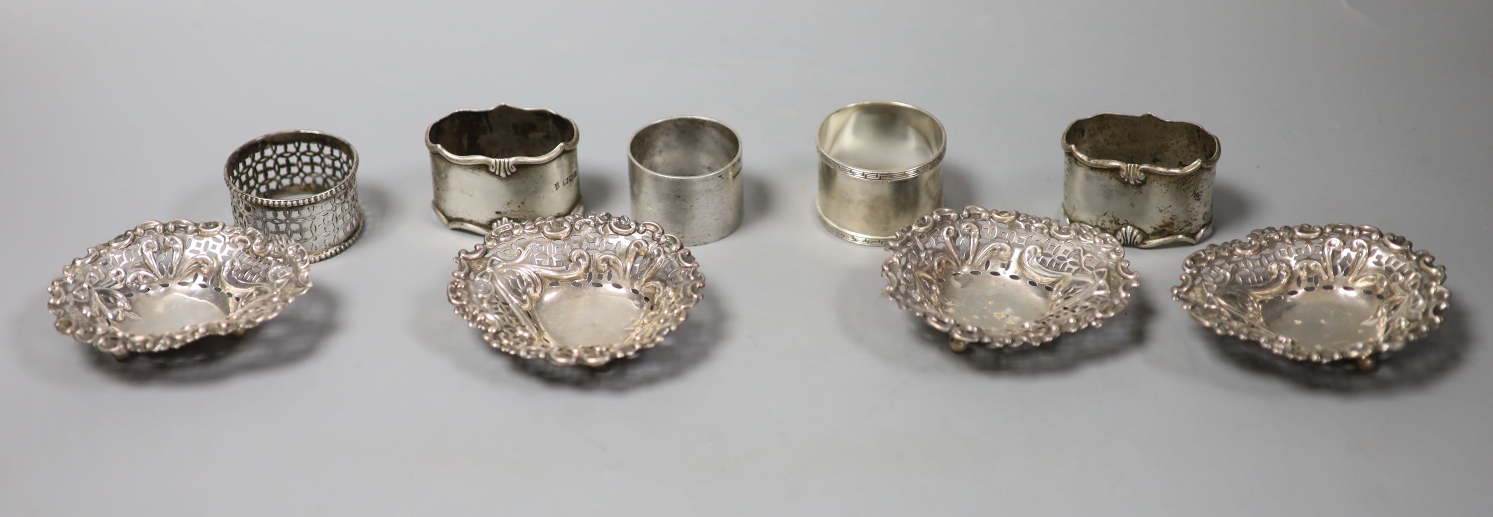 A pair of Edwardian silver napkin rings, London, 1906, three others and four pierced silver bonbon dishes